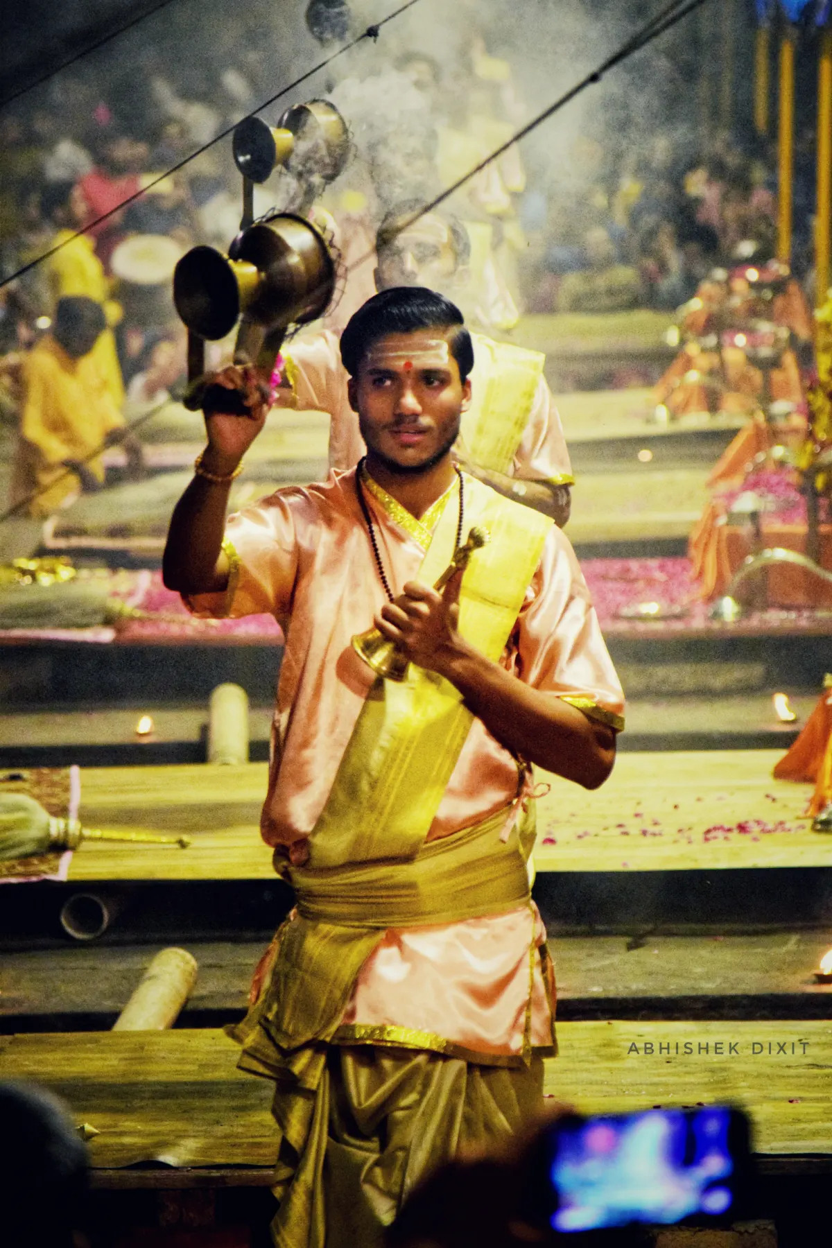 An aarti priest in yellow holding a lamp